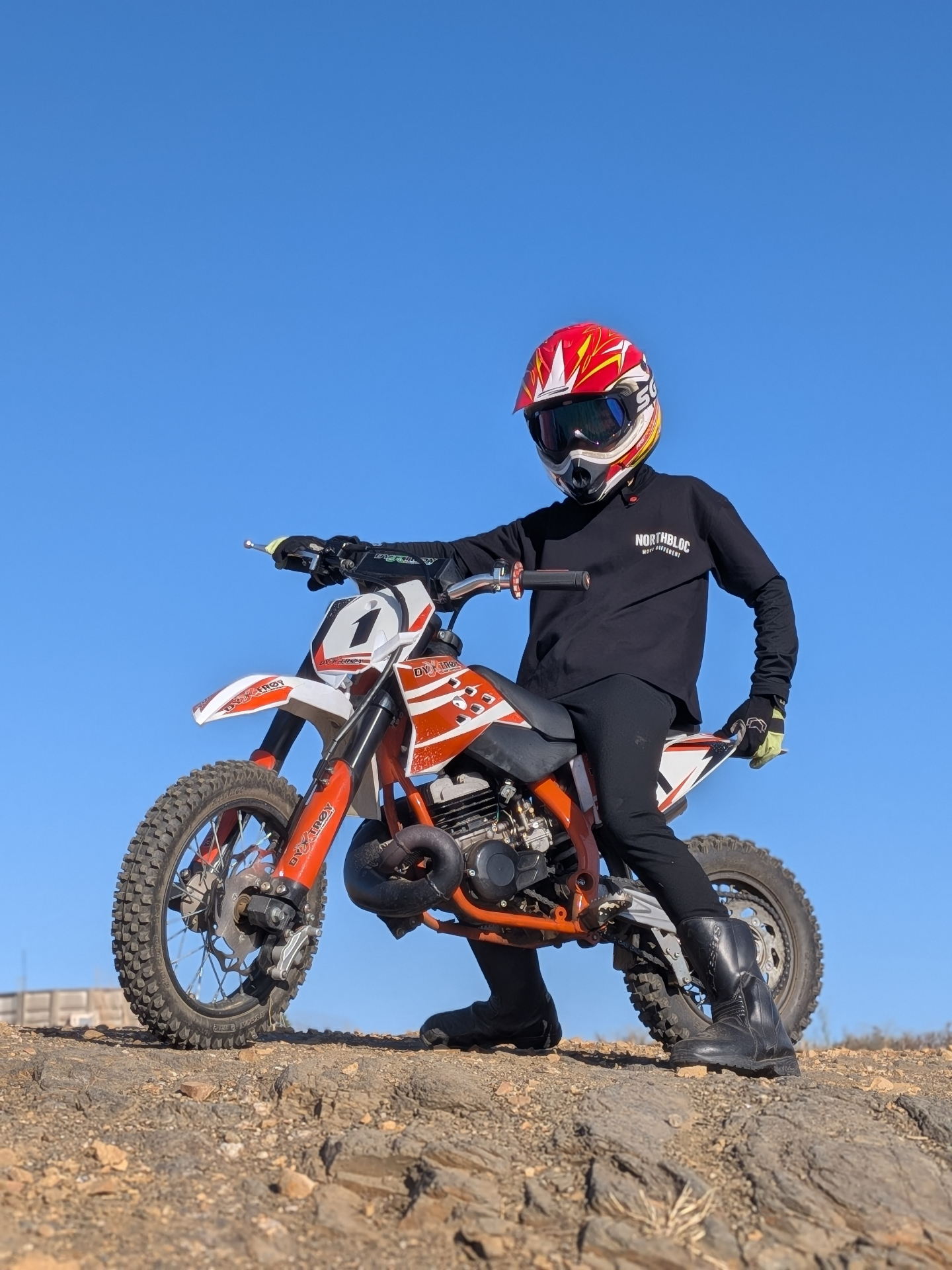 Rider in the black NORTHBLOC tee with the chest lockup, bike on dirt under open sky